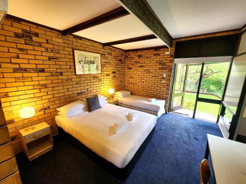 Un dormitorio con dos camas y una pared de ladrillo. en Fish Creek Hotel, en Fish Creek