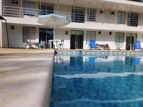 a swimming pool in front of a building with an umbrella at Lila Alojamiento Campestre in Melgar