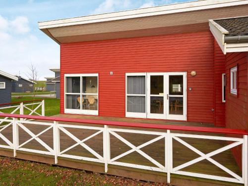 a red house with a white fence at Modern Retreat by Golf Course - By Traum Ferienwohnungen in Gudhjem