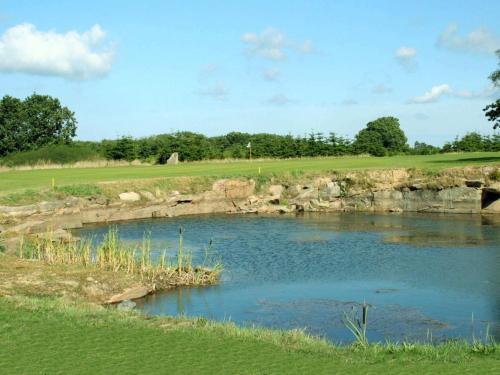 a golf course with a pond in the middle at Modern Retreat by Golf Course - By Traum Ferienwohnungen in Gudhjem