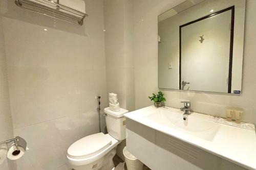a white bathroom with a toilet and a sink at LuxeLite Suites Pasay in Pasay