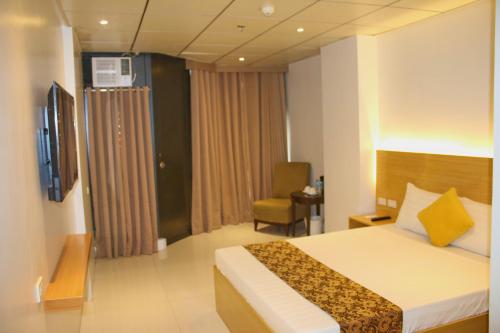 a hotel room with a bed and a chair at LuxeLite Suites Pasay in Pasay