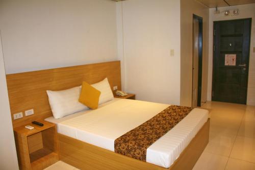 a bedroom with a large bed with a wooden headboard at LuxeLite Suites Pasay in Pasay