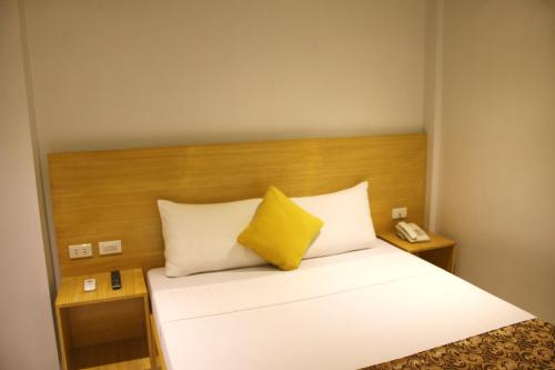 a hotel room with a bed with a yellow pillow at LuxeLite Suites Pasay in Pasay