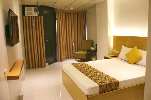 a hotel room with a bed and a chair at LuxeLite Suites Pasay in Pasay