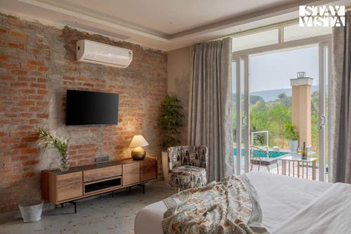a bedroom with a brick wall and a tv on a wall at StayVista at Kankas House - BBQ & Bonfire in Jaipur