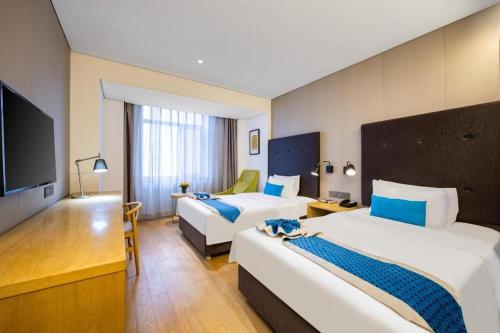 a hotel room with two beds and a flat screen tv at Yitel Shenyang Sanhao Street Shengjing Hospital in Shenyang