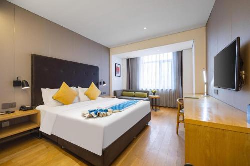 a hotel room with a large white bed and a flat screen tv at Yitel Shenyang Sanhao Street Shengjing Hospital in Shenyang