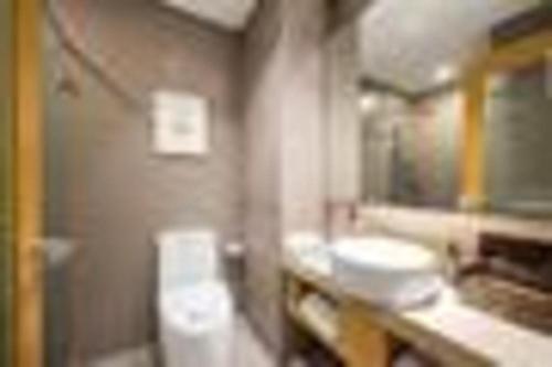 a bathroom with two sinks and a toilet and a mirror at Yitel Shenyang Sanhao Street Shengjing Hospital in Shenyang