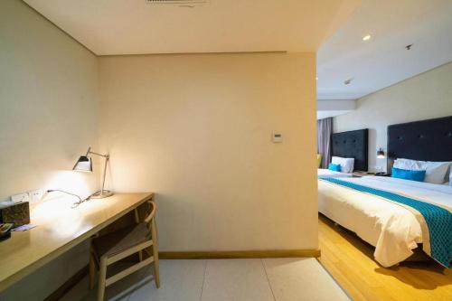 a bedroom with a bed and a desk with a lamp at Yitel Shenyang Sanhao Street Shengjing Hospital in Shenyang