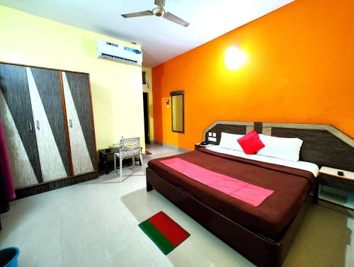 a bedroom with a bed with an orange wall at SEA-SIDE ROOFTOP VIEW- GARDEN -PARKING- Classic Hotel D-II PURI in Puri