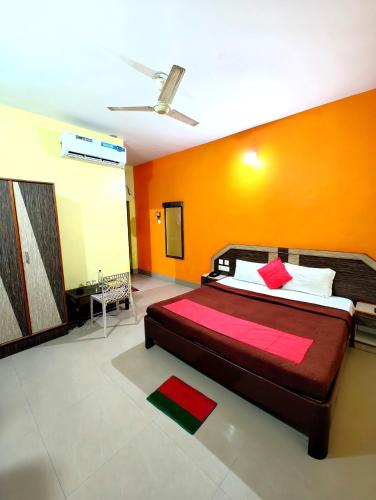 a bedroom with a bed with an orange wall at SEA-SIDE ROOFTOP VIEW- GARDEN -PARKING- Classic Hotel D-II PURI in Puri