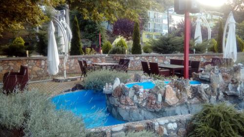 a garden with a fountain and a table and chairs at Apartments Kalistos in Star Dojran