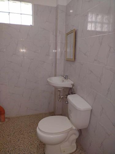 a white bathroom with a toilet and a sink at Suki Beach Resort "3-3" Family Aircon Room in Sorsogon