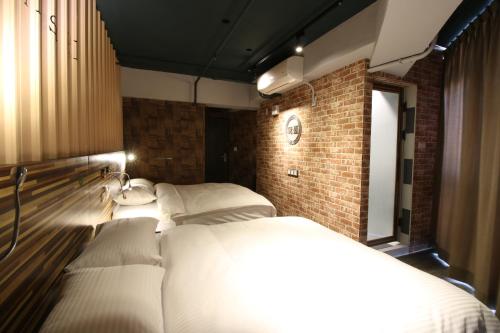 a room with three beds and a brick wall at R10 Eco Hotel in Kaohsiung