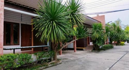 a building with palm trees in front of it at Kidthuengpark in Si Racha