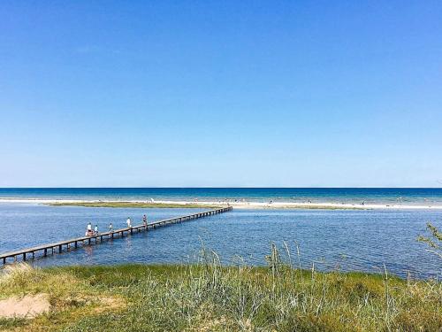 people walking on a pier over the water at the beach at 6 person holiday home in Hadsund in Øster Hurup
