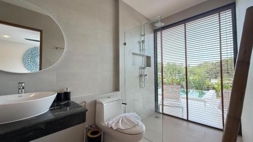 a bathroom with a sink and a toilet and a mirror at Suan Serenity Villa in Koh Samui