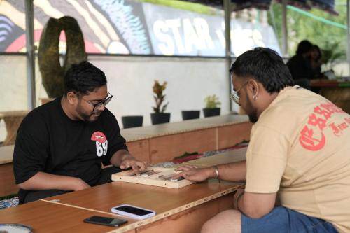 two men sitting at a table playing a video game at Star Vibes Resort in Jari
