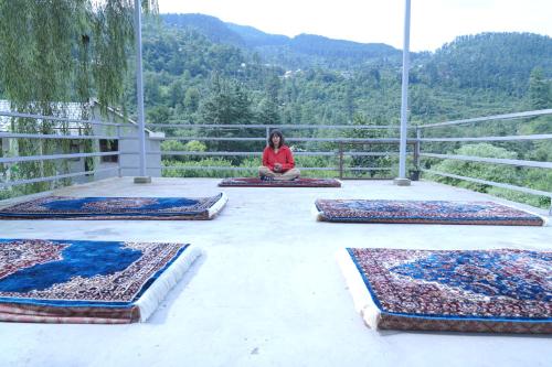 a woman sitting on a balcony with several rugs at Star Vibes Resort in Jari