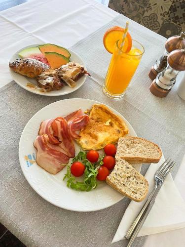 two plates of breakfast food on a table with orange juice at Hotel Riva Kaštela with swimming pool in Kaštela