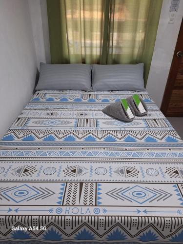 a bed with two pillows and two shoes on it at Rain Haven Lodging House in Coron