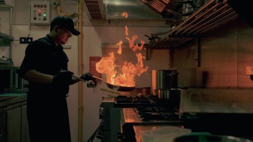 a man cooking food on a stove in a kitchen at Mira Hotel and Recovery in Uluwatu