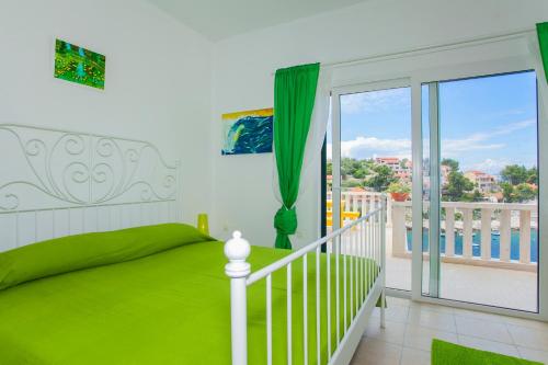 ein Schlafzimmer mit einem grünen Bett und einem Balkon in der Unterkunft Villa Lav in Prigradica