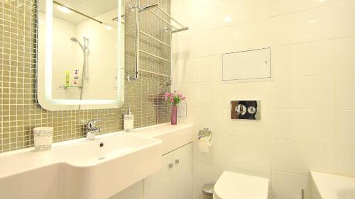 a white bathroom with a sink and a mirror at Apartment Evia Nord in Saint Petersburg