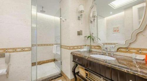 a bathroom with a sink and a shower and a mirror at Yin Run Jin Jiang Castle Hotel in Huzhou