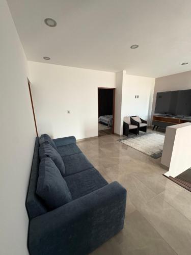 a living room with a blue couch and a television at New modern house in Qro in El Pueblito
