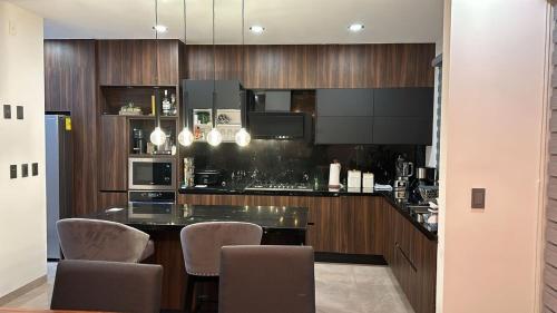 a kitchen with wooden cabinets and a counter with chairs at New modern house in Qro in El Pueblito