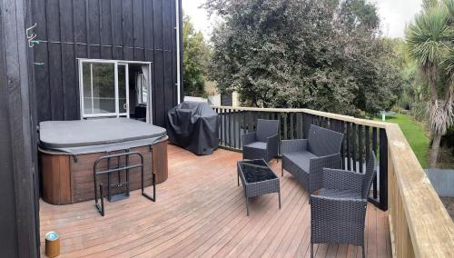 a deck with a bar and chairs on a building at Sun Saturated sanctuary in Timaru