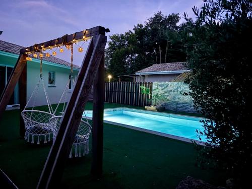un'altalena accanto alla piscina di notte di Maison 3 chambres avec piscine chauffée a Mios