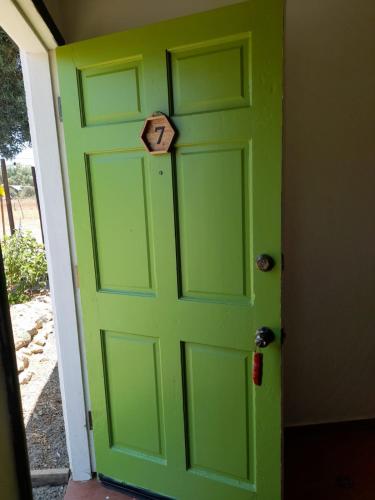 a green door with a wooden sign on it at Ranchito Boutique Motel Buhos Valle Guadalupe in Francisco Zarco