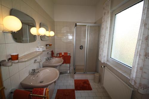łazienka z 2 umywalkami, prysznicem i oknem w obiekcie Parkhotel Phoenix Garni w mieście Hage