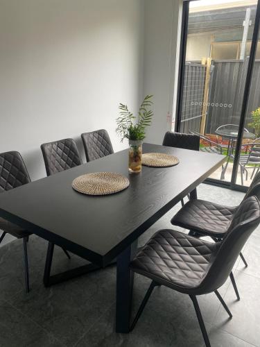 a black dining room table with chairs and a plant at Springvale 3 Bedroom Town House - Best Location in Springvale