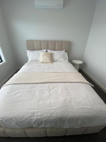 a large bed with a white comforter and a pillow at Springvale 3 Bedroom Town House - Best Location in Springvale