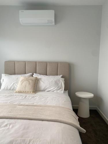 a bed with white sheets and a pillow and a table at Springvale 3 Bedroom Town House - Best Location in Springvale