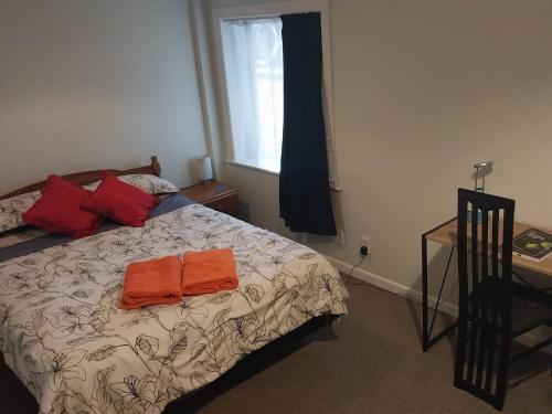 a bedroom with a bed with two orange towels on it at Charming Guest Room in Seatoun, Wellington in Miramar