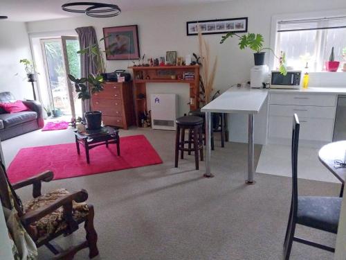 a kitchen and living room with a table and chairs at Charming Guest Room in Seatoun, Wellington in Miramar