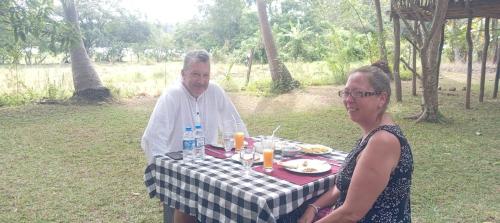 a man and a woman sitting at a table with food at Peacock Lake Villa in Habarana