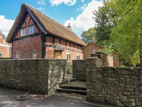 an old brick house with a stone wall at Manor Cottage in Church Stretton
