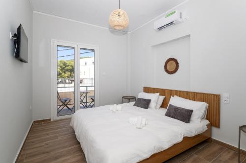 a bedroom with a large white bed and a balcony at Muse Studios & Apartments in Agia Marina Aegina