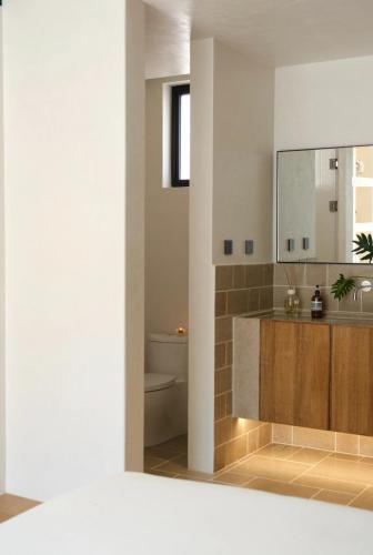 Un baño con lavabo, inodoro y espejo. en Ermington Luxury Villa, en Sídney