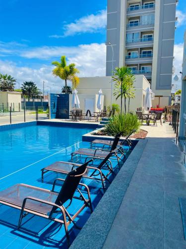 a swimming pool with chaise lounge chairs next to a building at Apartamento Ponta de Campina, 500m da Praia, com Vista Incrível do Pôr do Sol in Cabedelo