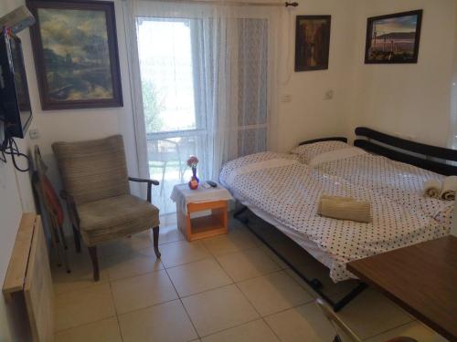 a bedroom with a bed and a chair and a window at Shapira in the Galilee in Bet Rimmon