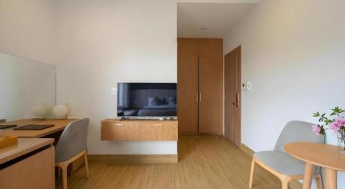 a living room with a television and a table and chairs at Gold View Boutique Hotel Đà Lạt in Da Lat