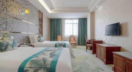 a hotel room with two beds and a television at Shenzhen Kai Long International Hotel in Shenzhen