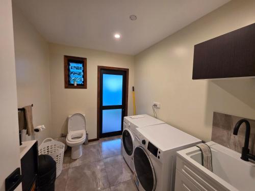 a bathroom with a washing machine and a toilet at Atupa Holiday Home in Rarotonga